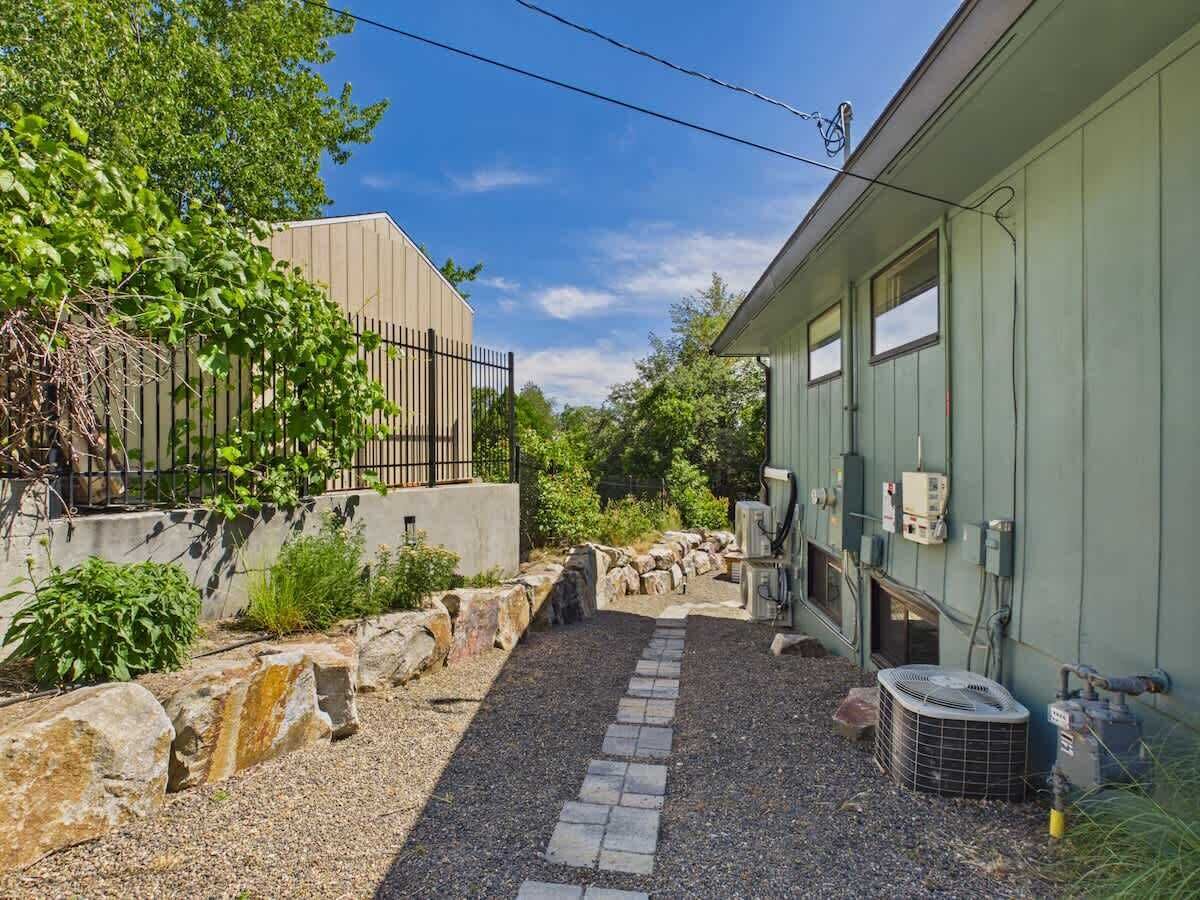 Un bâtiment avec un chemin de gravier, un mur en pierre et un appareil de climatisation.
