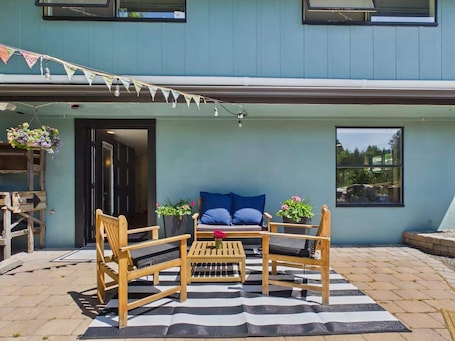 A patio with a wooden table and chairs, a blue sofa with cushions, and potted plants.. #StayinMyDistrict NE Boise Foothills Apartment