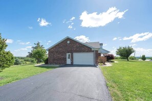 A single-story brick house with a garage, surrounded by a well-maintained lawn and trees.