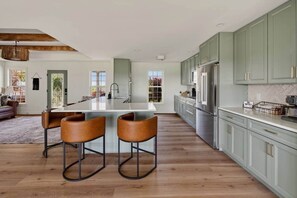 Uma cozinha espaçosa com ilha central, banquetas e eletrodomésticos modernos.