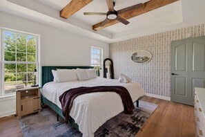 A bedroom with a bed, a ceiling fan, a window, and a door.