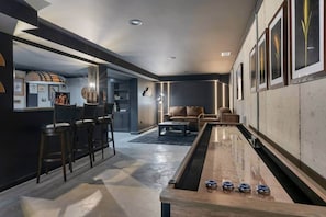 A modern interior with a pool table, bar area, and seating.