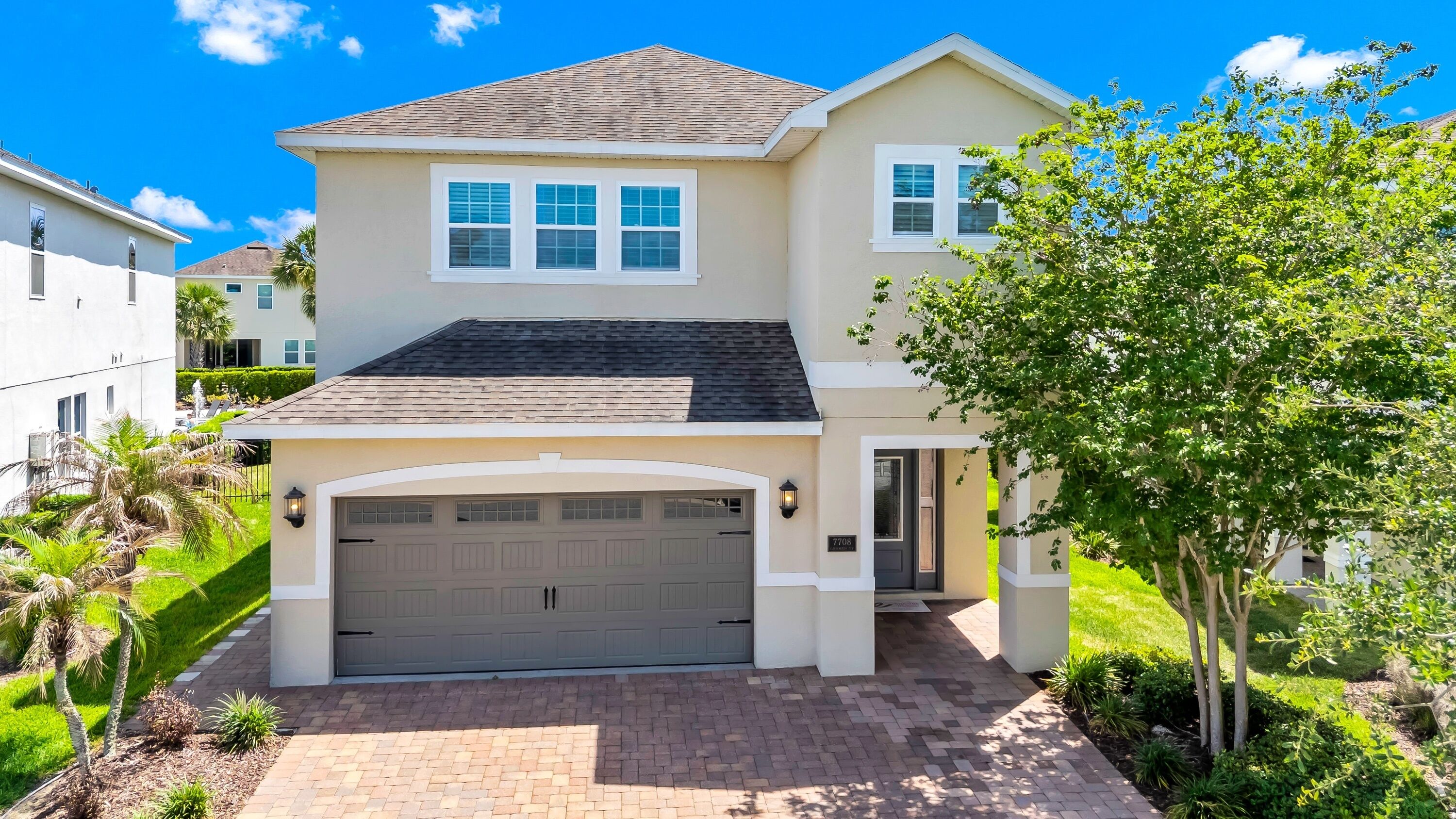 A two-story house with a garage, a driveway, and a well-maintained lawn.