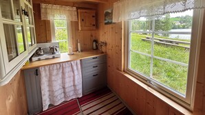 Cocina de cabaña de madera con vista al lago, estufa y lavabo.
