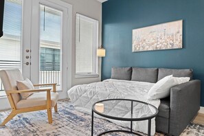 Ein Schlafzimmer mit einem Bett, einem grauen Sofa, einem runden Tisch und einem Sessel.