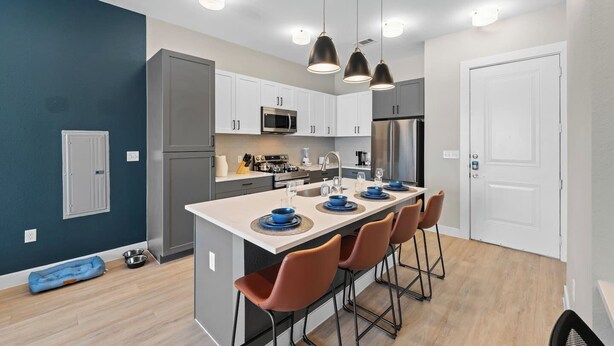 A modern kitchen with a central island, stainless steel appliances, and pendant lighting.