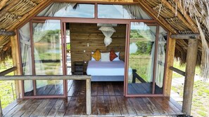 A wooden structure with a bed, a mosquito net, and a view of the outdoors. - Ecopayara Hotel Puerto Gaitán (Puerto Gaitán)