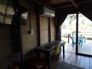 A wooden interior with a table and chairs, an air conditioning unit, and a view of the outdoors. - Ecopayara Hotel Puerto Gaitán (Puerto Gaitán)
