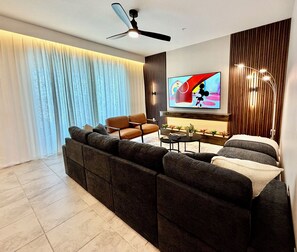 Ein modernes Wohnzimmer mit einer Couch, einem Couchtisch, einem Fernseher und einem Deckenventilator.