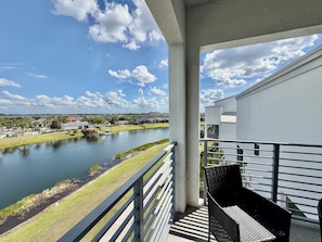 Ein Balkon mit Blick auf einen Fluss, eine Grünfläche und ein weißes Gebäude im Hintergrund.