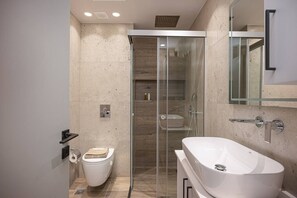 Ein modernes Badezimmer mit einer gläsernen Duschkabine, einer freistehenden Badewanne und einem WC mit Handtuch.