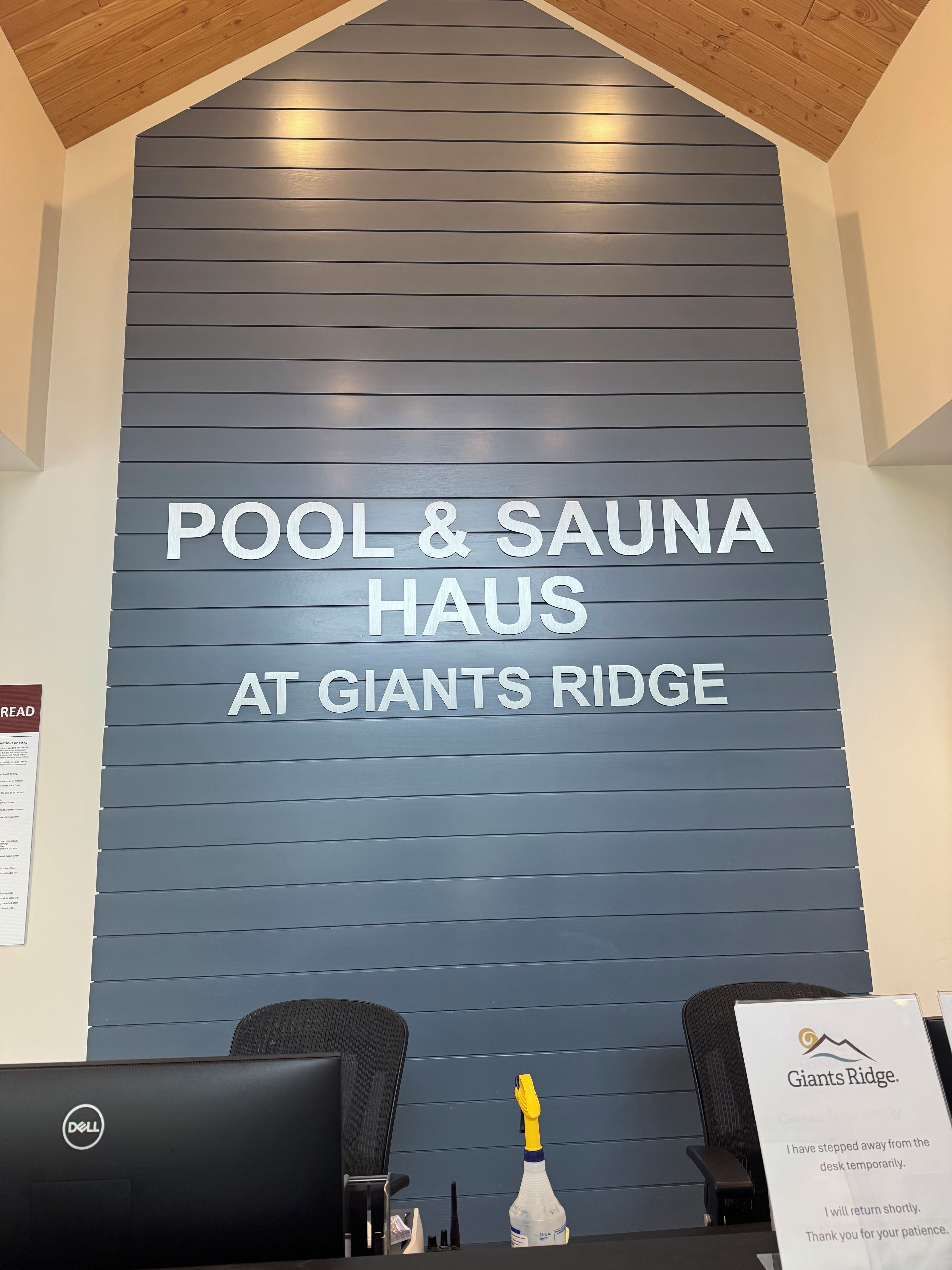Een receptiegedeelte met een bordje voor 'POOL & SAUNA HAUS AT GIANTS RIDGE' en een bericht over tijdelijke afwezigheid van de receptie.'