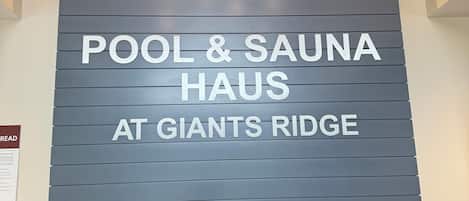 Un área de recepción con un cartel que indica 'POOL & SAUNA HAUS AT GIANTS RIDGE' y un aviso sobre la ausencia temporal de la recepción.