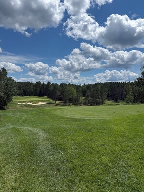 Ein Golfplatz mit Sandbunkern und bewaldeter Umgebung.