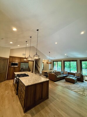 Une cuisine spacieuse dotée d’un grand îlot central, de meubles en bois et d’appareils électroménagers en acier inoxydable.