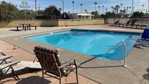 A swimming pool with lounge chairs, a fence, and a sign for Desert Grove Inn & Suites. - Budgetel Inn & Suites (Yuma)