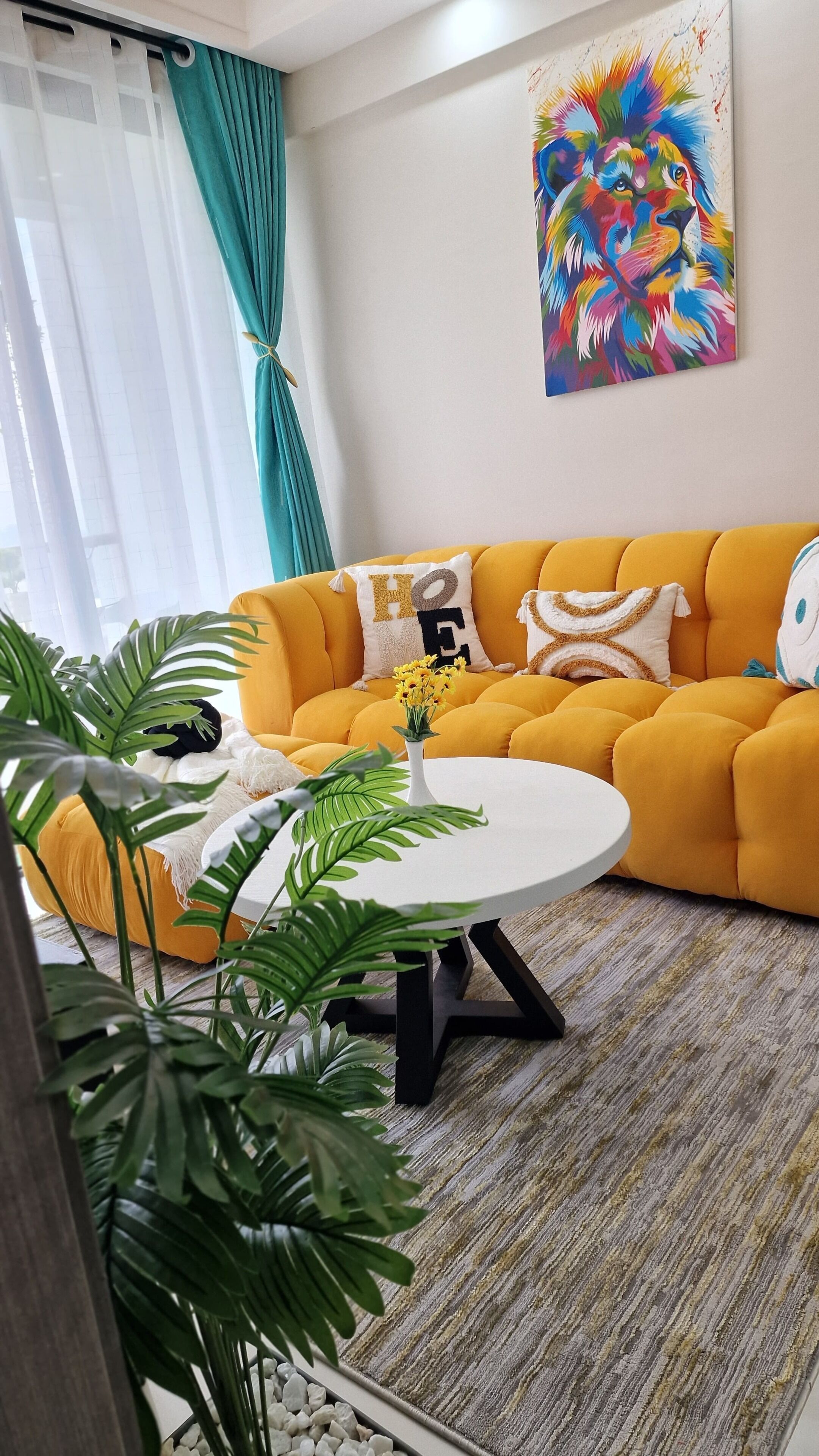 A living room with a yellow sofa, a round coffee table, and a painting on the wall.