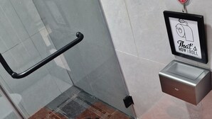 A bathroom with a shower, a toilet, a sink, and a framed picture on the wall. - Stylish High-Rise Retreat, Skyline Views, Gym & Rooftop in Kilimani (Nairobi)