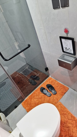 Ein Badezimmer mit Dusche, Toilette, Waschbecken und einem gerahmten Bild an der Wand.