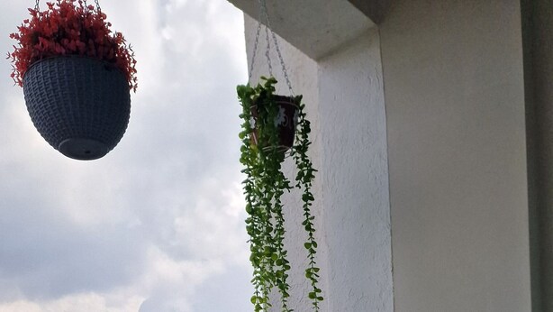 A balcony with a glass table, white chairs, a small potted plant, and a hanging planter. - Stylish High-Rise Retreat, Skyline Views, Gym & Rooftop in Kilimani (Nairobi)