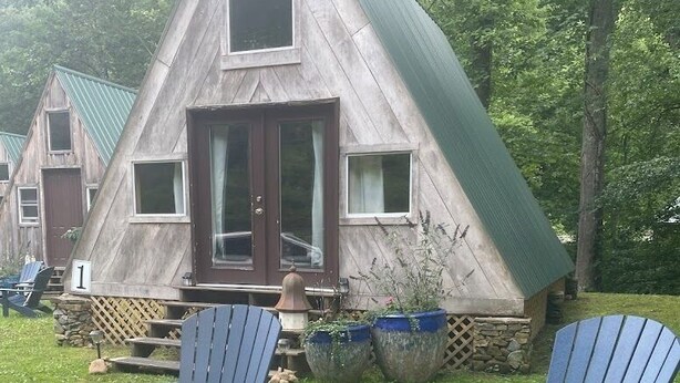 A cabin with a triangular roof, a fire pit, and two Adirondack chairs. - A-Frame Cabin -The Get Away #1 (Diana)
