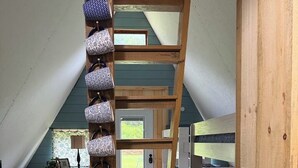 Ein Schlafzimmer im Loft-Stil mit einer Holzleiter, einer Kaffeemaschine und einem Mülleimer.