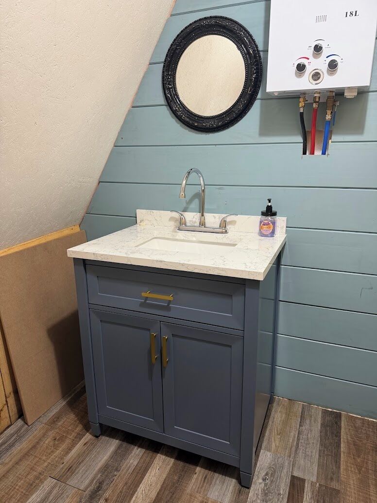 Ein Badezimmer mit Waschbecken, Spiegel und Wand-Wasserhitzer.