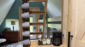 Ein Loft-Zimmer mit Holzleiter, einer Kaffeestation und Blick ins Freie.