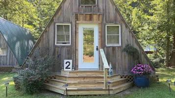A wooden cabin with a white door, two windows, and a number '2' sign.