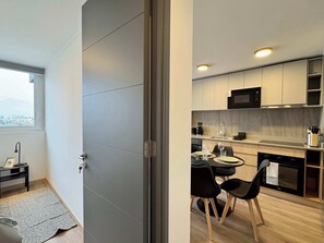 Una cucina moderna con zona pranzo, vista attraverso una porta e un piccolo tavolo con sedie.