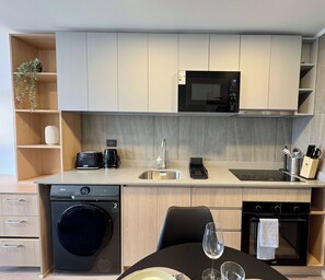 A compact kitchen with a microwave, sink, and integrated dishwasher. - 2BR Andes View - Parking, Pool & Metro (Santiago)