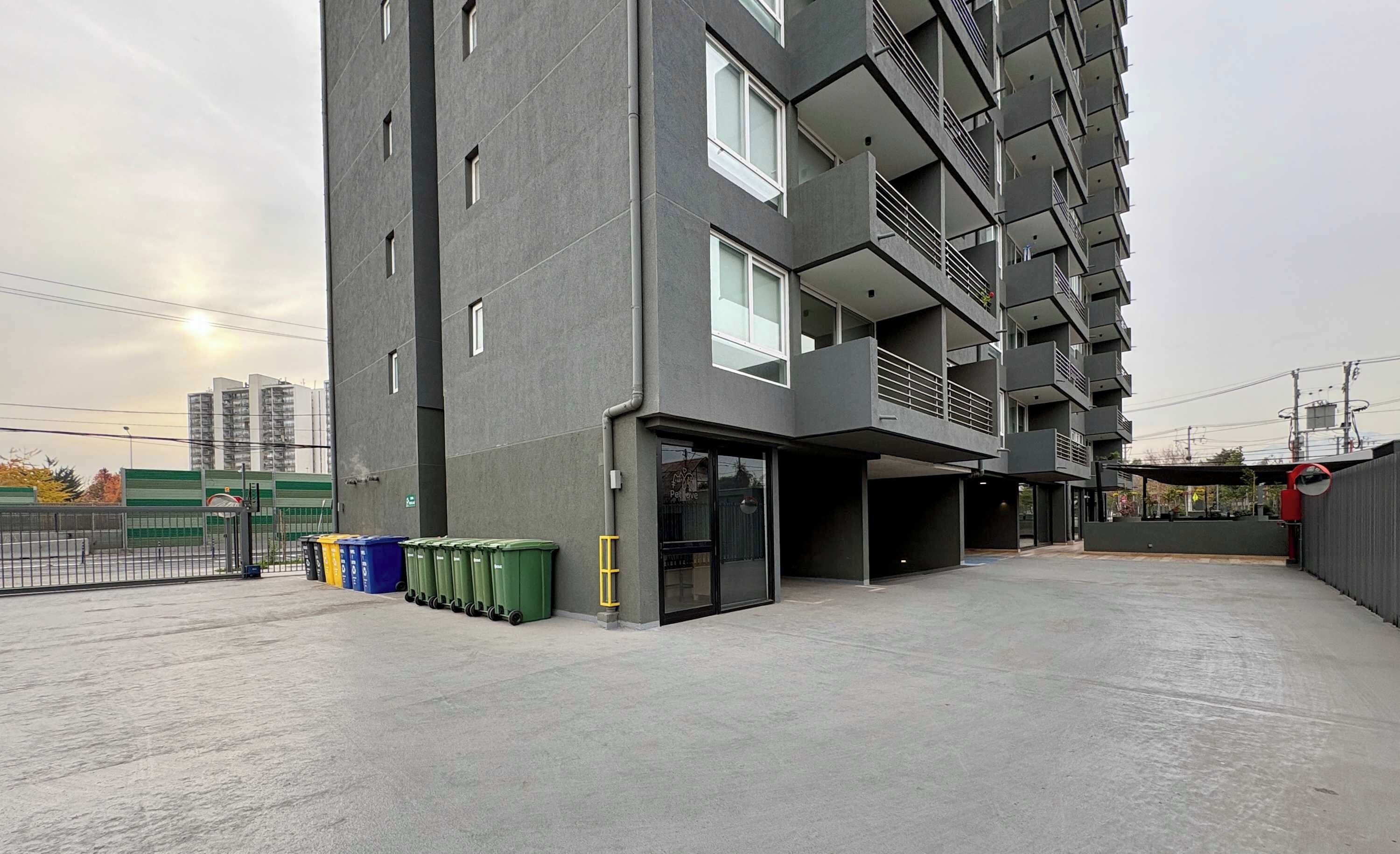Un edificio de varios pisos con fachada plana, ventanas grandes y una entrada protegida por una reja.