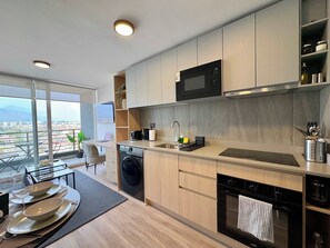 A modern kitchen with a dishwasher, oven, and microwave. - 2BR Andes View - Parking, Pool & Metro (Santiago)
