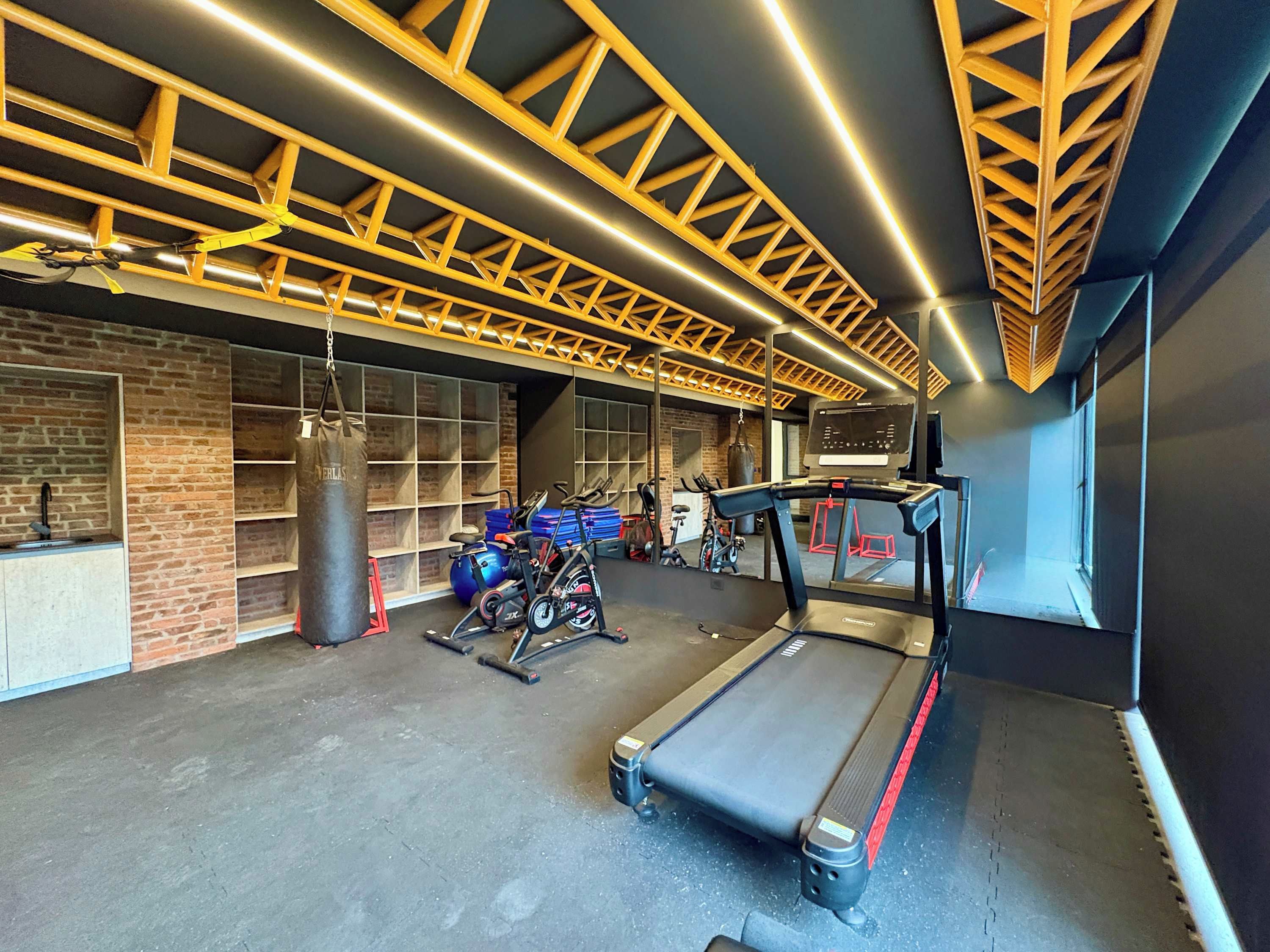 Un gimnasio con equipo de ejercicio, un saco de boxeo y una cinta de correr.