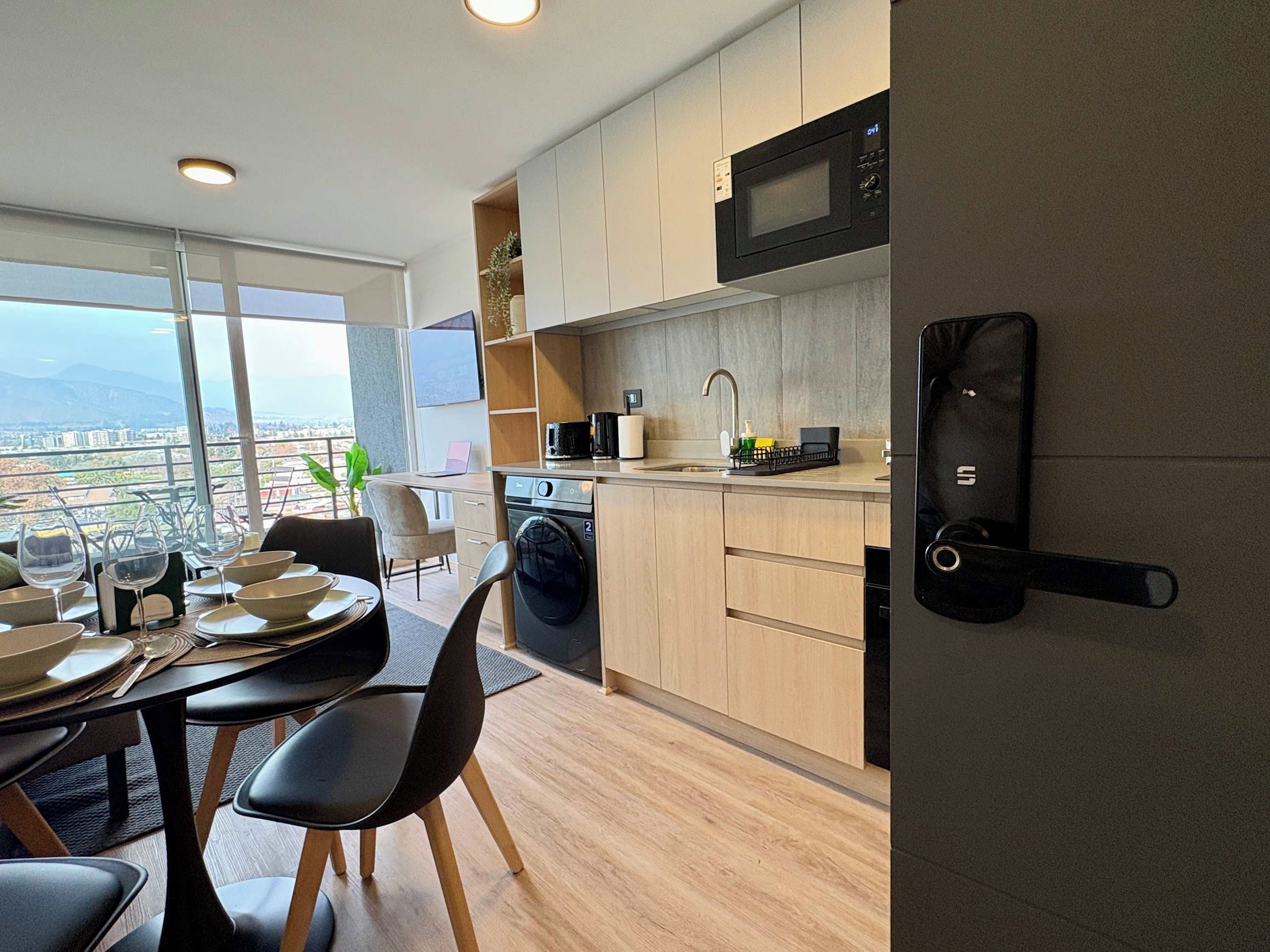 A modern kitchen with a view, a dining area with a table set, and a door with a lock.