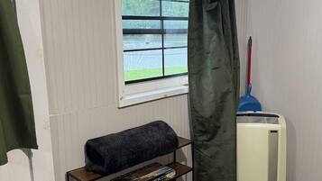 A room with a window, a radiator, a shelf with books, and a curtain.