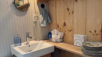 A bathroom with a wooden vanity, a sink, a mirror, a towel rack, and a fan.