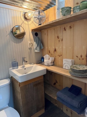 A bathroom with a wooden vanity, a sink, a mirror, a towel rack, and a fan.
