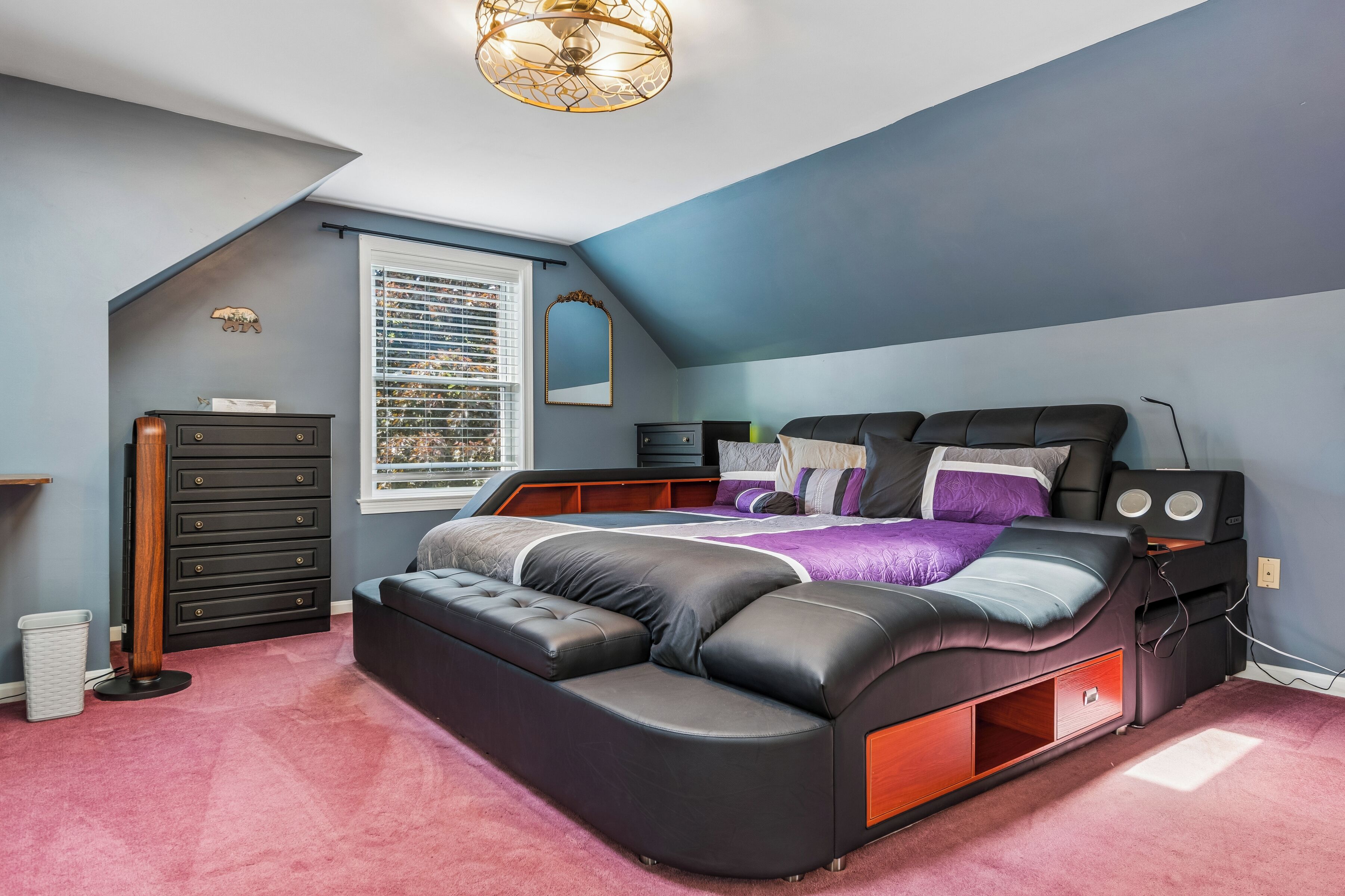 A bedroom with a bed, dresser, and window with blinds.