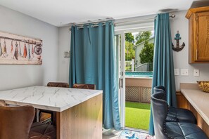 Un coin repas avec une table en marbre, des chaises en cuir et une vue sur le jardin à travers une porte vitrée.