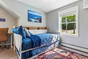 Une chambre à coucher avec un lit, un bureau, une chaise, une fenêtre donnant sur un beau paysage et un tableau accroché au mur.