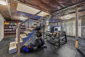 A gym with weightlifting equipment, a staircase, and a workout bench. - Pool, Dream Home Gym, TV+Desk in Each Room, 85" TV, Games, 2 BKB Hoops, Fire Pit (Lewiston)