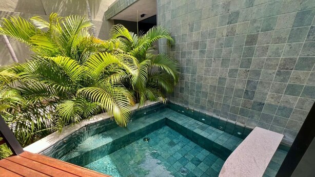 Tinaco rectangular con agua cristalina, rodeado de paredes de azulejos y una terraza de madera.