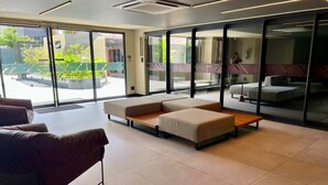 Un moderno vestíbulo de hotel con un sofá modular, una mesita y un gran ventanal con vistas al exterior.