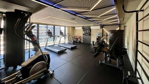 Un gimnasio con cintas de correr, elípticas y equipo de pesas.