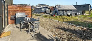 Eine Terrasse im Freien mit Grill, Tisch und Stühlen.