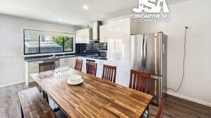 Eine moderne Küche mit weißen Schränken, einem Holzespeisetisch und einem Kühlschrank aus Edelstahl.