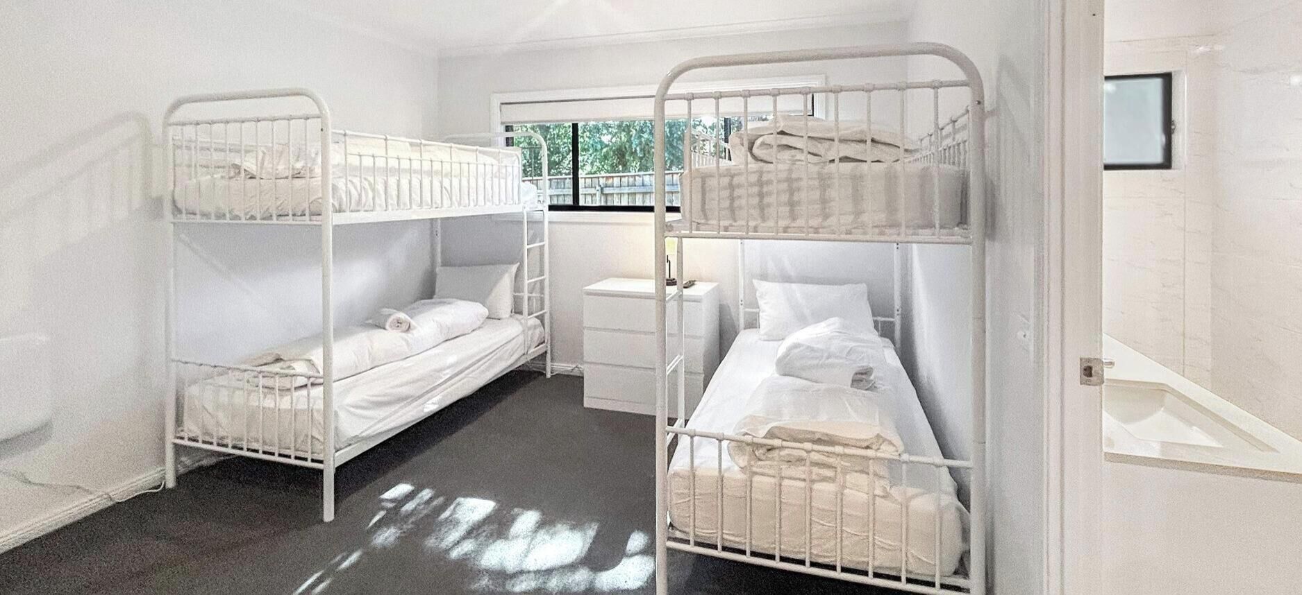 A room with bunk beds, a small bedside table, and a window with a view.