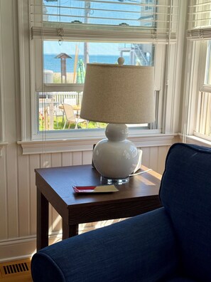 A room with a table, a lamp, and a view of the outdoors.