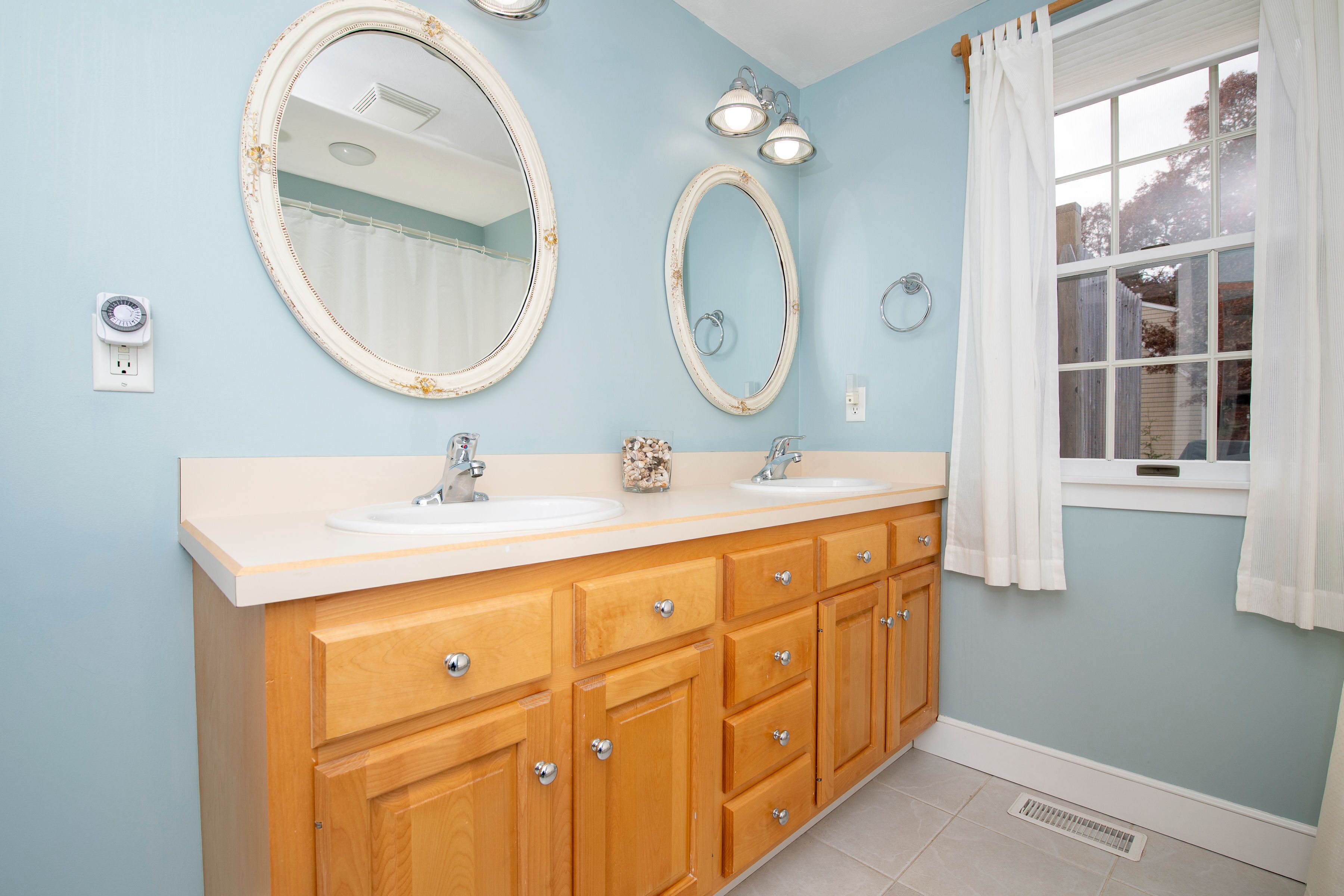 A bathroom with two sinks, wooden cabinets, and two wall-mounted mirrors.